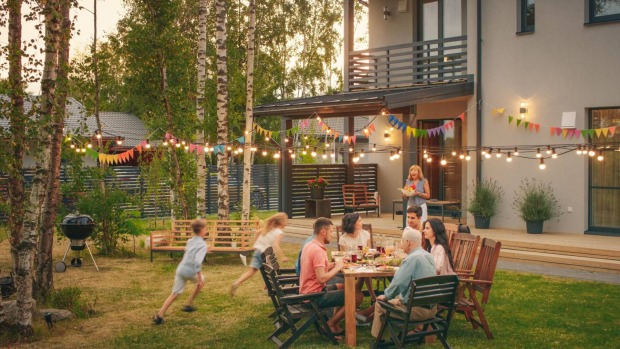 Familie beim gemeinsamen Essen in einem Garten in der Abenddämmerung.
