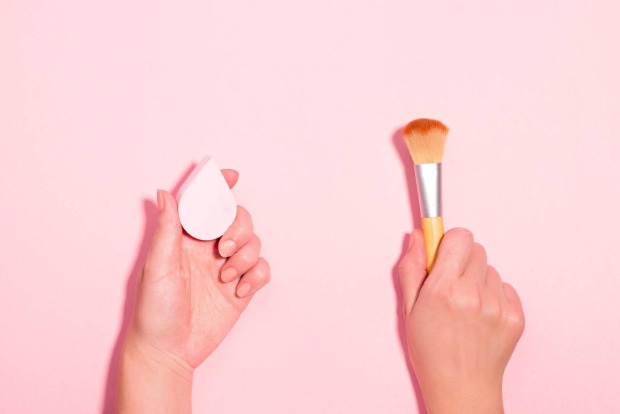 Aufnahme von zwei Händen: In der linken Hand befindet sich ein Beauty-Sponge und in der rechten ein Make-up-Pinsel.