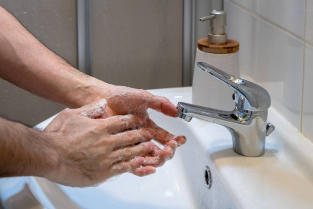 Hände, die im Waschbecken mit Seife und Wasser gewaschen werden