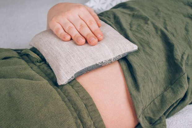 Wärmekissen, das bei Menstruationsbeschwerden gegen den Unterleib gedrückt wird