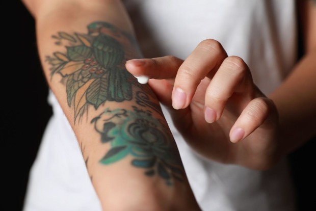 Eine Frau pflegt ihr Tattoo mit einer Creme.
