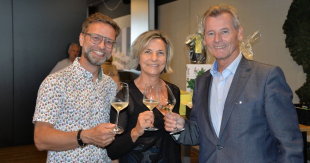 Zwei Männer und eine Frau stoßen mit einem Glas Sekt an