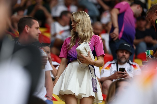Eine blonde Frau im weißen Rock steht auf der Tribüne