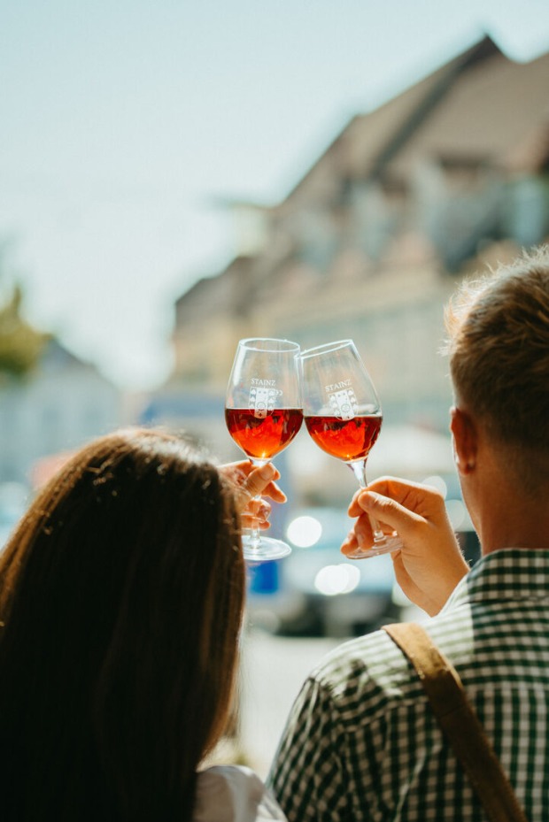 Ein Paar stoßt vor einer Stadtkulisse mit Wein an