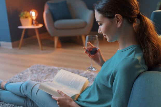 Frau sitzt im Wohnzimmer und liest | Credit: iStock.com/demaerre