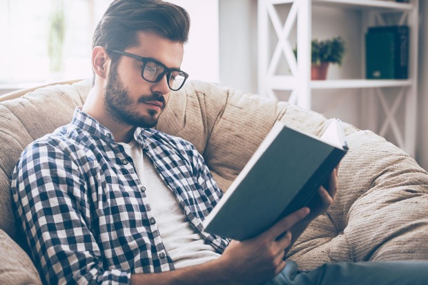 Mann sitzt auf Couch und liest | Credit: iStock.com/g-stockstudio