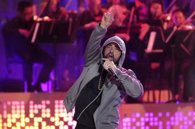 Der Rapper Eminem singt vor einem Orchester auf einer Bühne in ein Mikrophon