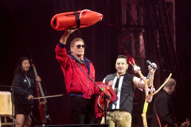 David Hasselhoff, der eine rote "Baywatch"-Jacke trägt und eine rote Rettungsboje in die Höhe streckt, auf der Bühne mit Andreas Gabalier