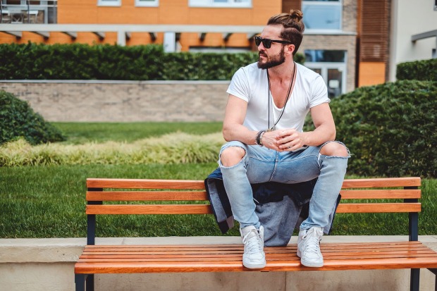 Mann in Jeans sitzt auf einer Bank | Credit: iStock.com/Sjale