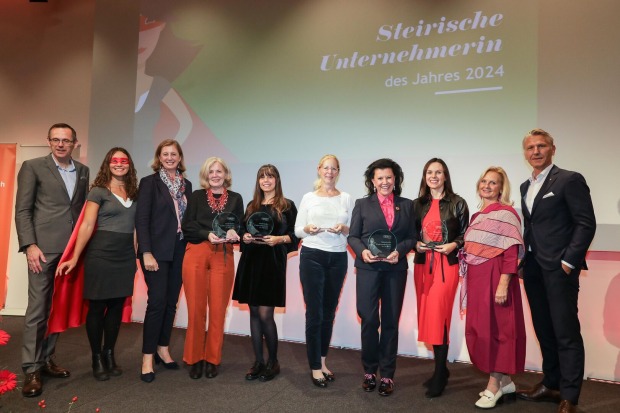 Mehrere Menschen posieren auf einer Bühne für ein Foto