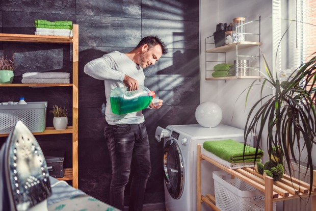 Mann füllt Waschmittel in die Waschmaschine | Credit: iStock.com/Kerkez