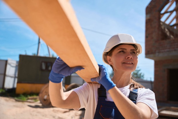 Tischlerin schultert eine Holzbahre | Credit: iStock.com/yacobchuk