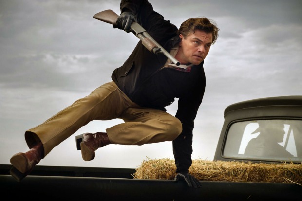Szenenfoto aus "Once Upon a Time in Hollywood", das Leonardo DiCaprio zeigt, wie er, mit einem Gewehr in der Hand, über das Heck eines Jeeps Pickups springt