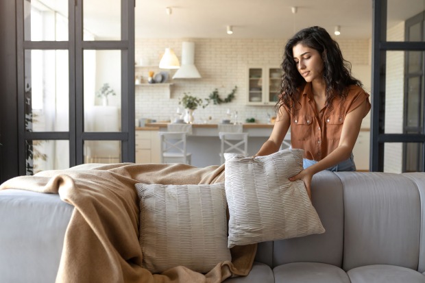 Frau dekoriert Sofa | Credit: iStock.com/Prostock-Studio