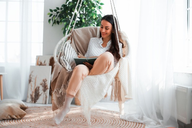 Frau liest in einem Hängesessel | Credit: iStock.com/Povozniuk