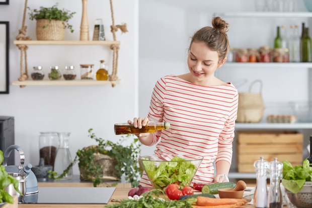 Frau gibt Olivenöl in ihren Salat | Credit: iStock.com/KatarzynaBialasiewicz