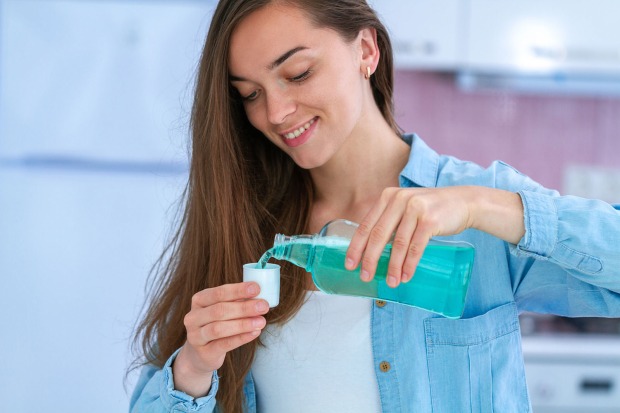 Frau gibt Mundwasser in Becher | Credit: iStock.com/Siarhei Khaletski