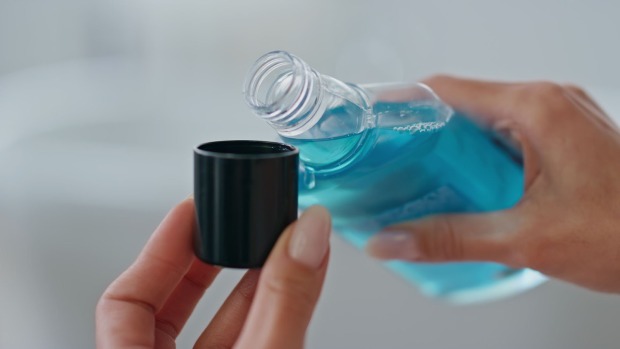 Frau gibt Mundwasser in einen Becher | Credit: iStock.com/stockbusters