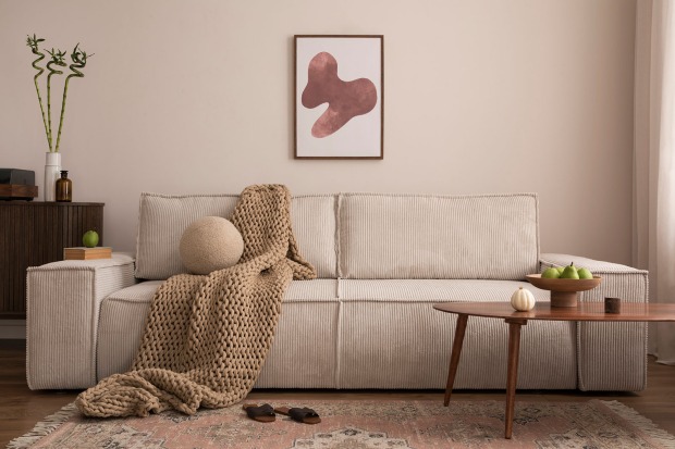 Beige Couch mit einer Wolldecke | Credit: iStock.com/FollowTheFlow
