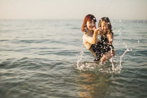 Eine rothaarige Mutter und ihre Tochter baden im Meer