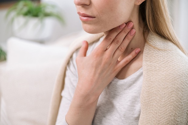 Frau hält sich Hand an Hals | Credit: iStock.com/brizmaker