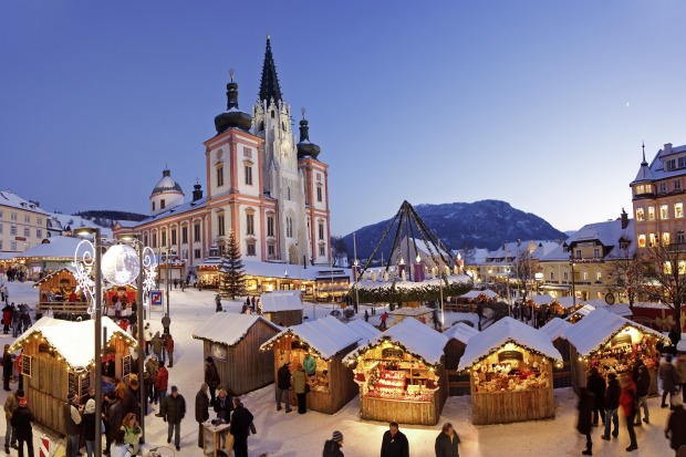 Ein Adventmarkt beim Sonnenuntergang, dahinter eine Basilika