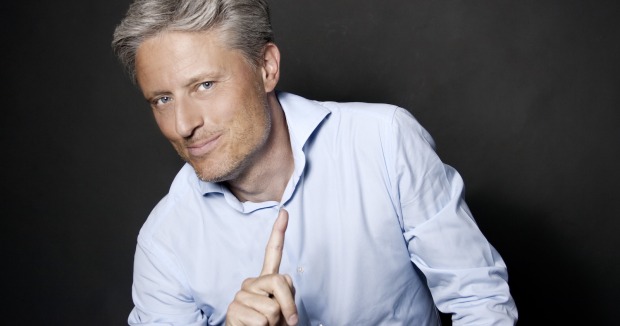 Florian Scheuba im hellen Hemd und mit erhobenem Zeigefinger
