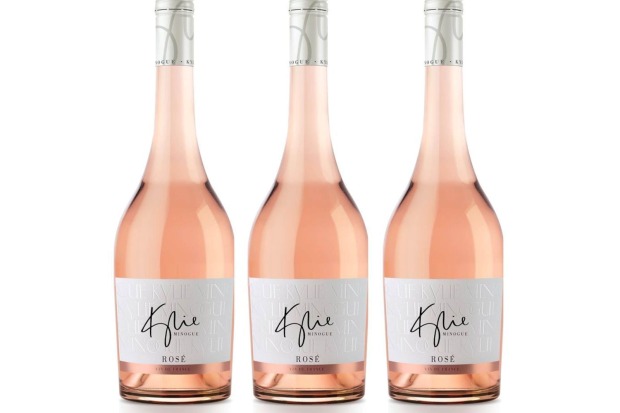 Drei roséfarbene Weinflaschen der Marke Kylie Minogue Rosé stehen nebeneinander vor weißem Hintergrund.