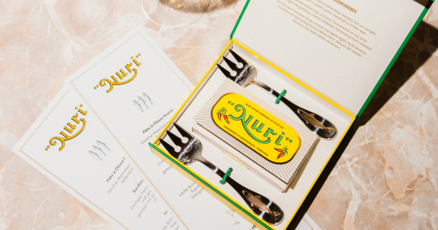 zwei vergoldete Sardinengabeln in einer Geschenkbox mit einer Dose Sadrinen