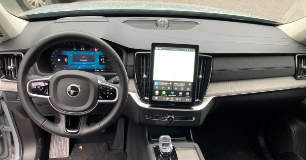 Das Armaturenbrett sowie das Lenkrad des Volvo XC90 sind in grau gehalten. Zu sehen ist auch ein Display in der Mitte des Fahrzeugs.