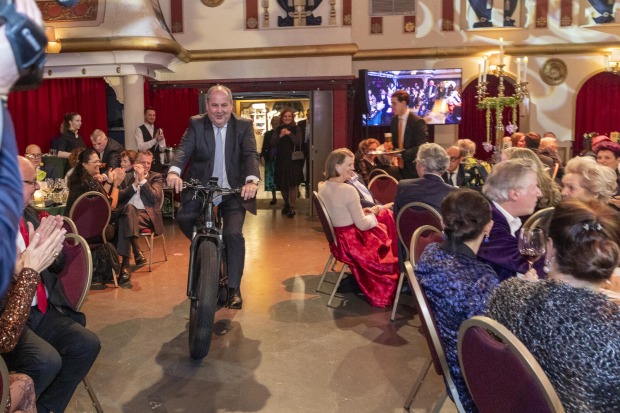 Erwin Pröll fährt in den Saal auf einem Rad ein