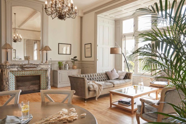 Eleganter Salon im Château Les Carrasses mit Kronleuchter, Kamin, hohen Fenstern und klassischer Einrichtung.  Titel