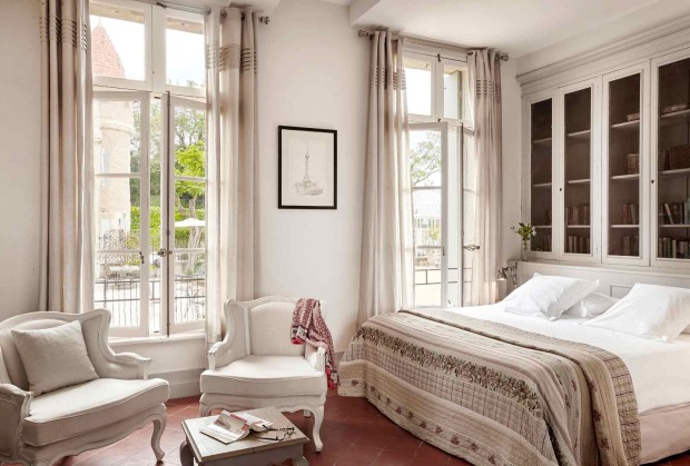 Helles Gästezimmer im Château Les Carrasses mit französischen Fenstern, klassischem Mobiliar und Blick ins Grüne.