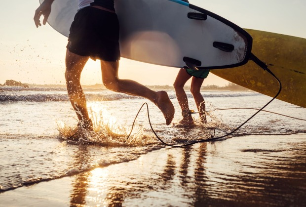 Zwei Surfer laufen mit ihren Brettern in das Meer.