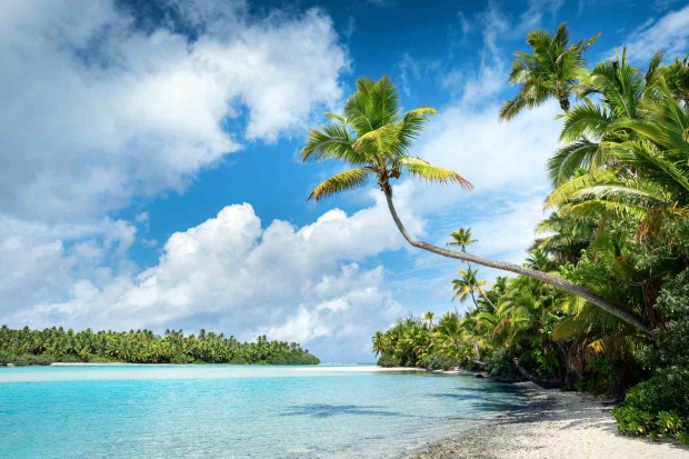 Tropischer Strand auf Aitutaki mit schräger Palme, weißem Sand und ruhigem, türkisfarbenem Wasser.