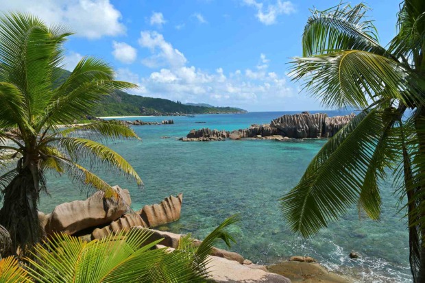 Tropische Bucht Anse Marron auf La Digue mit Palmen, türkisfarbenem Wasser und markanten Granitfelsen.