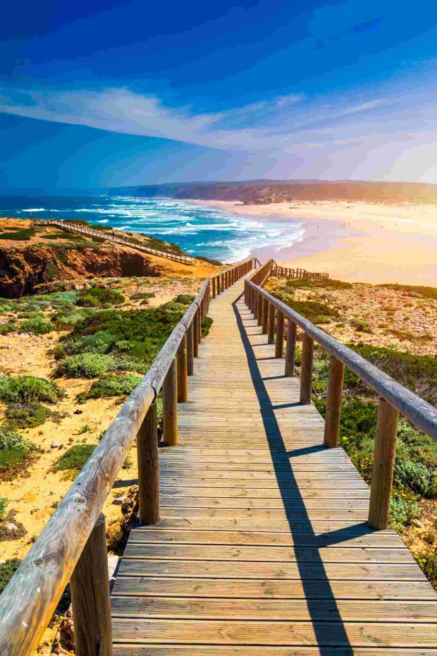 Holzsteg führt durch Dünenlandschaft hinunter zum Strand von Carrapateira an der portugiesischen Atlantikküste.