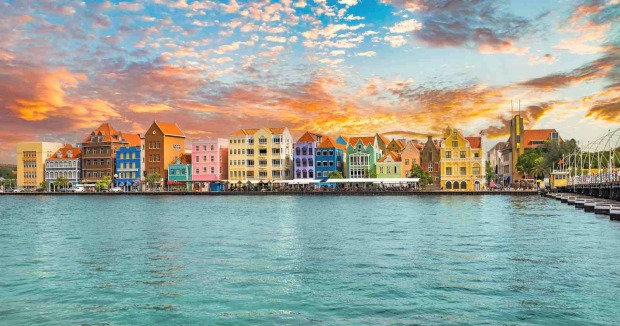 Bunte Häuserzeile an der Uferpromenade von Willemstad auf Curaçao bei Sonnenuntergang