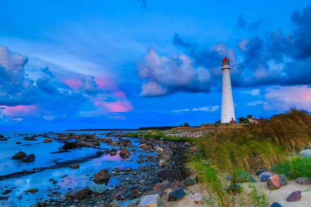 Leuchtturm auf Hiiumaa in Estland an einer steinigen Küste mit Gras, Meer und dramatischem Himmel.