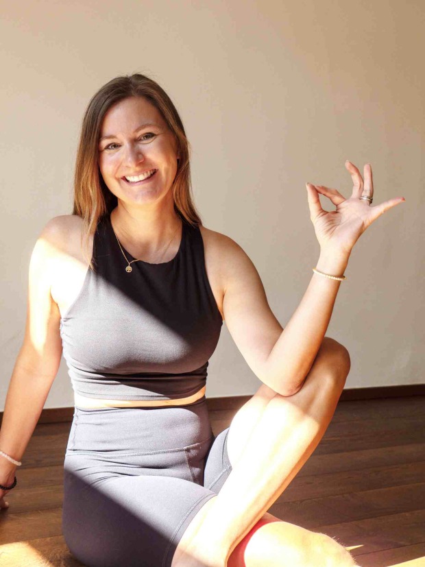 Katharina Tschurtschenthaler sitzt in Yoga-Kleidung auf dem Boden und lächelt