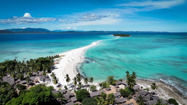 Luftaufnahme von Nosy Iranja mit weißer Sandbank, die zwei Inseln im türkisblauen Meer verbindet, umgeben von Palmen und klarem Wasser.