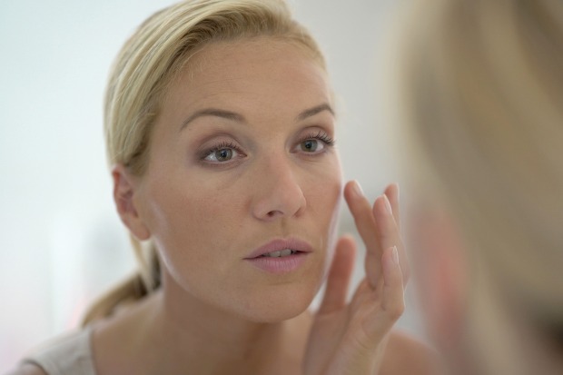 Frau bei der Hautpflege vor dem Spiegel | Credit: goodluz/Shutterstock