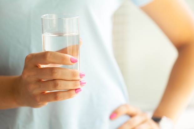 Ein Glas Wasser in der Hand einer Frau | Credit: FabrikaSimf/Shutterstock
