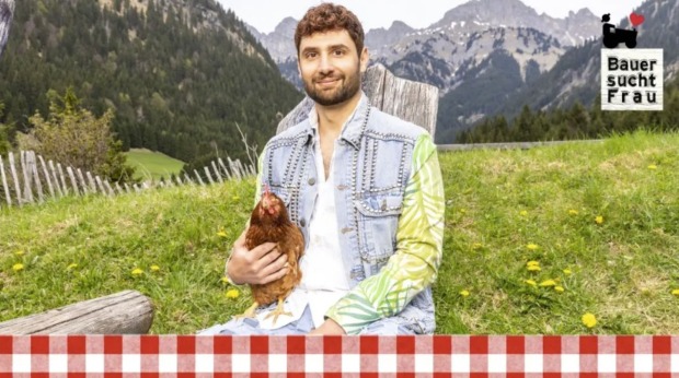 „Bauer sucht Frau“-Kandidat Kevin aus Tirol mit Huhn vor Bergkulisse in der neuen Staffel von „Bauer sucht Frau“