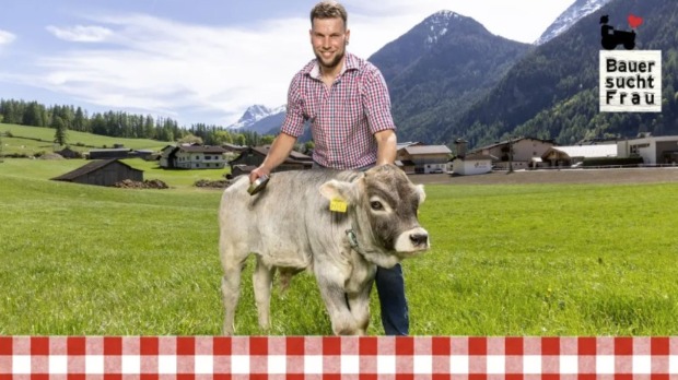 „Bauer sucht Frau“-Kandidat Tobias aus Tirol mit Kalb auf einer Almwiese in der neuen Staffel von „Bauer sucht Frau“