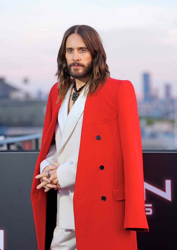 Jared Leto mit langen Haaren und Bart in rotem Mantel bei einem aktuellen Event.