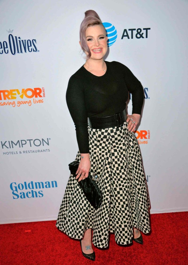 Kelly Osbourne posiert auf dem roten Teppich in schwarzem Oberteil und gemustertem Rock mit auffälliger Frisur.