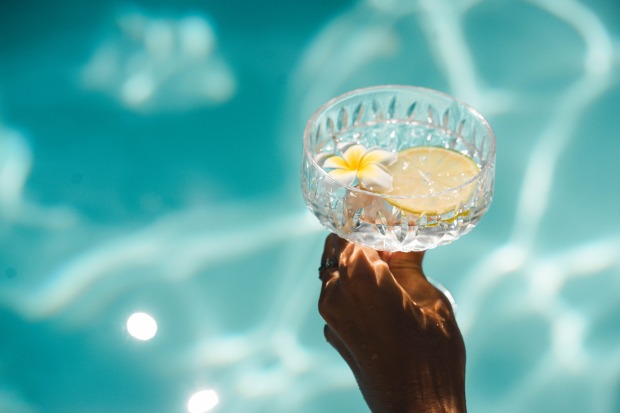 Frau am Pool mit Drink in der Hand | Credit: lara yarochevska/Shutterstock