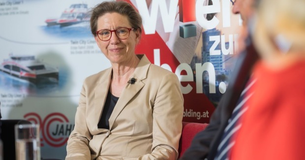 Karin Ramser im Gespräch vor einer Werbewand
