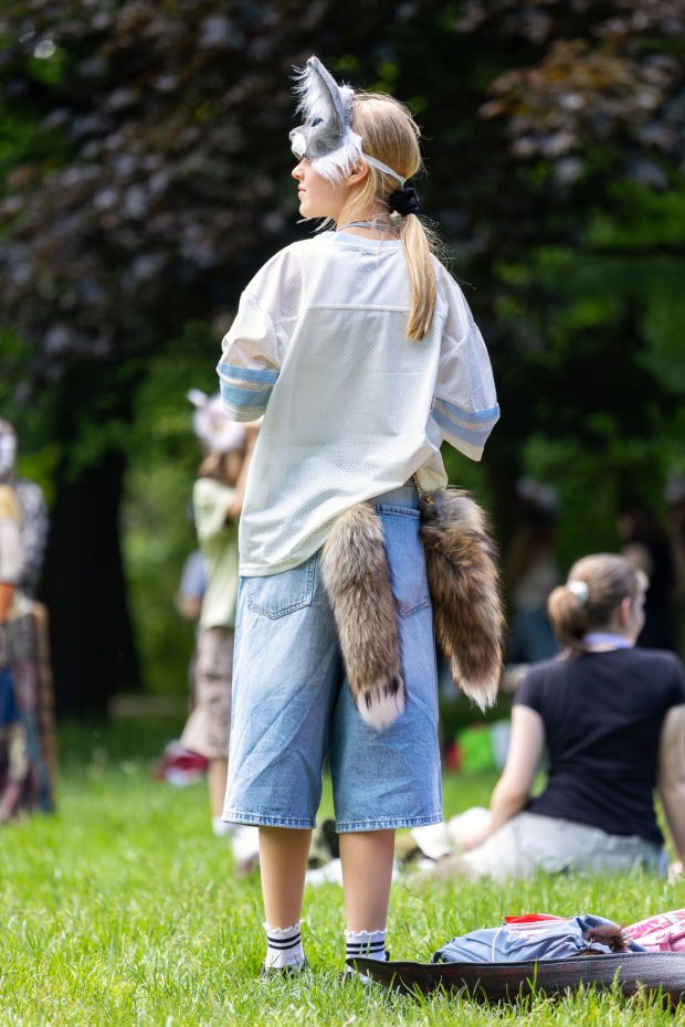 Ein Mädchen trägt einen Schwanz und eine Tiermaske.